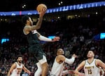 Portland Trail Blazers guard Anfernee Simons, top, shoots a game-winning basket over Denver Nuggets guard Russell Westbrook, center, and center Nikola Jokic (15) during the second half of an NBA basketball game in Portland, Ore., Thursday, Dec. 19, 2024.