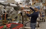 AquaHarmonics CEO Alex Hagmüller holds his small prototype wave energy converter up to the larger model currently in development in this video screen shot from April 2025. The company began laying off staff on June 30, 2025 after their promised federal grant research funding was not released by the Trump administration.