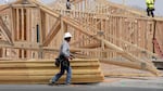 Construction workers install a lumber roof on a new home.