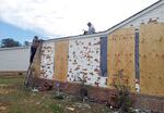 John Purry secures tarps on the roof of his house in Pearl, Miss., Wednesday, March 20, 2013 with the help of his uncle, Amos Wilson, left, covering up damage from Monday's hail storm that hit central Mississippi. Purry believes he is in a race against time as another round of severe weather threatens. Hail broke windows, shattered siding and left holes in his roof.