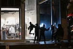 Youths break a store window during clashes between protestors and police in Paris, Sunday, Oct. 18, 2026.