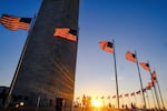 Tourists walk around the base of the Washington Monument as the sun sets.