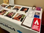 A table covered with a cloth featuring the Loyola Marymount Hillel logo in the front, and six portraits of hostages who were killed sitting on top of it.