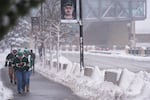Fans walk through snowy streets before an NHL hockey game between the Minnesota Wild and Toronto Maple Leafs, Sunday, March 15, 2026, in St. Paul.