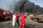 In this photo provided by Islamic Republic News Agency (IRNA), firefighters work as black smoke rises in the sky after a massive explosion rocked a port near the southern city of Bandar Abbas, Iran on Saturday.