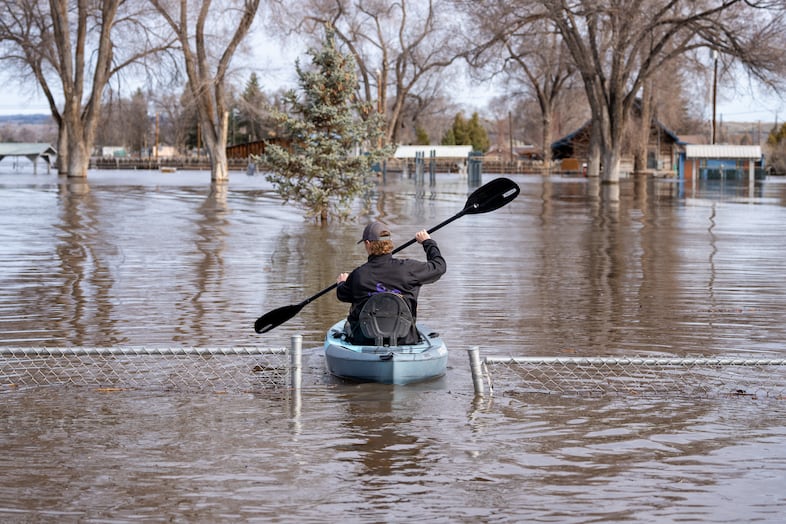 Area residents paddle through the flooded Triangle Park to provide aid to homeowners along North Broadway Avenue in Burns, Ore., March 30, 2025. 