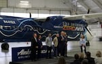 Politicians and corporate leaders gathered in a Paine Field hangar to celebrate the handover of a retired Alaska Airlines Q400 turboprop, which will be converted to hydrogen-electric propulsion over the next year.