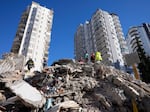 Emergency teams search for people in the rubble of a destroyed building in Adana, southern Turkey, Tuesday, Feb. 7, 2023. For Syrians and Ukrainians fleeing the violence back home, the earthquake that struck in Turkey and Syria is but the latest tragedy.