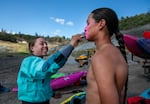 Ruby Williams of the Quartz Valley and Karuk tribes (left), uses a zinc sunscreen stick on ‘ A:de’ts-Nikya:w Rogers (right) of the Hoopa Valley Tribe alongside an old dam construction site on the banks of the Klamath River, June 22, 2025.