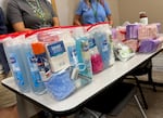A foldout table with clear bags of toiletries like soap, razors, and pads.
