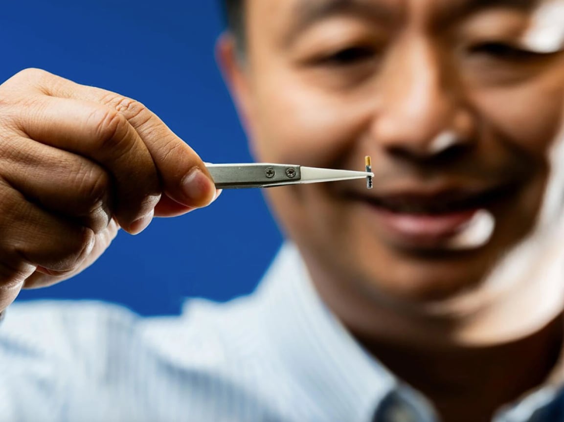 Daniel Deng, a scientist at Pacific Northwest National Laboratory, holds SHAD-TAGS+ with a pair of tweezers. The tiny acoustic tag helps researchers monitor fish species and life stages that were previously