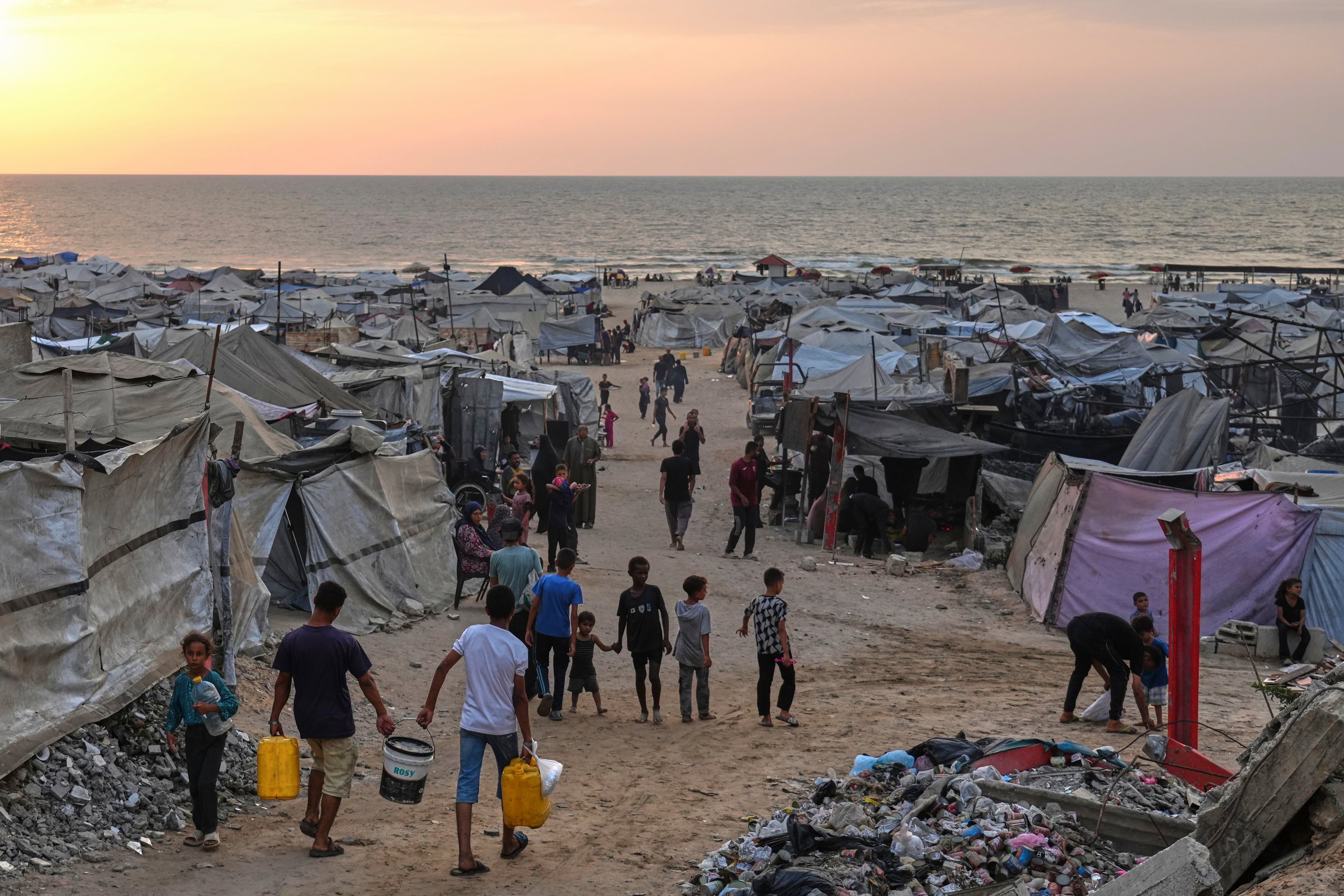 Displaced Palestinians walk through a makeshift camp along the beach in Gaza City on Sunday.