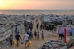 Displaced Palestinians walk through a makeshift camp along the beach in Gaza City on Sunday.