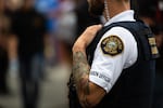 A liaison officer with the Portland Police Bureau watches people at a rally organized by the Proud Boys, labeled a hate group by the Southern Poverty Law Center, in Portland, Ore., Saturday, Aug. 17, 2019.