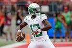 A person in a white University of Oregon football uniform gets ready to throw a football.