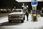 A man fills up on gas during the snowstorm. 