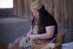 Stephanie Craig is a seventh-generation basket weaver, artist and enrolled member of the Confederated Tribes of Grand Ronde whose exhibit, "Hands of the Ancestors" is on display from April 2 - May 2, 2025 at Linfield University's Miller Fine Arts Center. Craig is shown in this photo taken in summer 2024 at the achaf-hammi plankhouse in the Grand Ronde Reservation weaving a wa'paas, or Columbia Plateau basket used for gathering roots.