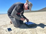 Alan Case identifies one of his arrows in the Alvord Desert in July, 2023, taking notes and using his phone's GPS to measure the distance the arrow flew.