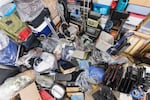 Pile of objects accumulated in someone's home including clothing and outdoor equipment, household objects, and old electronics.