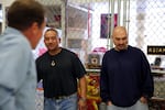 Walter Taitinfong (left) and Johnny Cofer (right) in front of the Asian Pacific Family Club "cage" at the Oregon State Penitentiary activities floor. Taitinfong is the club's secretary, and Cofer is the garden's project manager. 