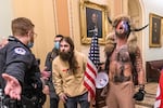 FILE - Supporters of President Donald Trump, including Jacob Chansley, right with fur hat, are confronted by U.S. Capitol Police officers outside the Senate chamber inside the Capitol during the capitol riot in Washington, Jan. 6, 2021. Chansley was sentenced on Wednesday, Nov. 17, 2021, to 41 months in prison for his felony conviction for obstructing an official proceeding. Though he wasn't accused of violence, Chansley acknowledged he was among the first 30 rioters in the building, offered thanks while in the Senate for having the chance to get rid of traitors and wrote a threatening note to Vice President Mike Pence.