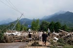 Local residents walks in front of a damaged road littered with broken tree branches after a heavy rains in Taishitun Town, Miyun district on the outskirts of Beijing, China, on Monday.