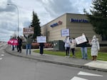 People hold signs on street corner. Some of the messages on the signs include: "Racism is a virus," and "Stop Asian Hate."