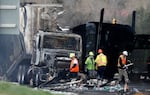 FILE - Workers clear debris from the eastbound lanes of Interstate 70 on April 26, 2019, in Lakewood, Colo., following a deadly pileup involving a semi-truck hauling lumber. A truck driver who was convicted of causing the fiery pileup that killed four people and injured six others on Interstate 70 west of Denver was sentenced Monday, Dec. 13, 2021, to 110 years in prison. Rogel Aguilera-Mederos was convicted in October of vehicular homicide and other charges stemming from the April 2019 crash.