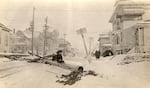 A woman sits on fallen utility poll at NE 19th & Weidler after a snow storm, Dec. 31, 1917.
