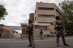 Customs and Border Protection agents wearing camouflage uniforms stand on a street outside a multistory Immigration and Customs Enforcement facility in Portland, Oregon, on October 4.