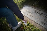 Roberta Gorg cleans the Wippel family's gravestone at Riverview Cemetery on December 10, 2019.