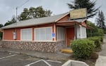 A cottage-style restaurant with orange siding and white windows. A sign reads The Prescott Cafe / Homestyle Cooking.