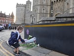 Queen Elizabeth II's death sets a succession apparatus in motion that has been dormant for decades. Here, a youngster leaves flowers outside Windsor Castle on Thursday.