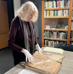 Cynthia Basye looks at an a scrapbook compiled by Daiichi Takeoka during his incarceration in Santa Fe, N.M., at the library of Japanese American Museum of Oregon in Portland, Ore., on April 30, 2024.