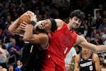 Phoenix Suns guard Devin Booker (1) gets fouled by Portland Trail Blazers forward Deni Avdija (8) during the second half of an NBA play-in tournament basketball game, Tuesday, April 14, 2026, in Phoenix.