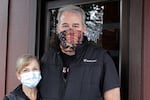 Liz and Bryan Mitchell, co-owners of the Carver Hangar, pose outside their restaurant in Boring, Ore., on Jan. 6, 2021. The restaurant is one of dozens of restaurants around the country defying state bans on indoor dining enacted due to the spread of COVID-19. In Oregon, the defiance has led to a crackdown by state regulators and thousands of dollars in fines for some establishments.