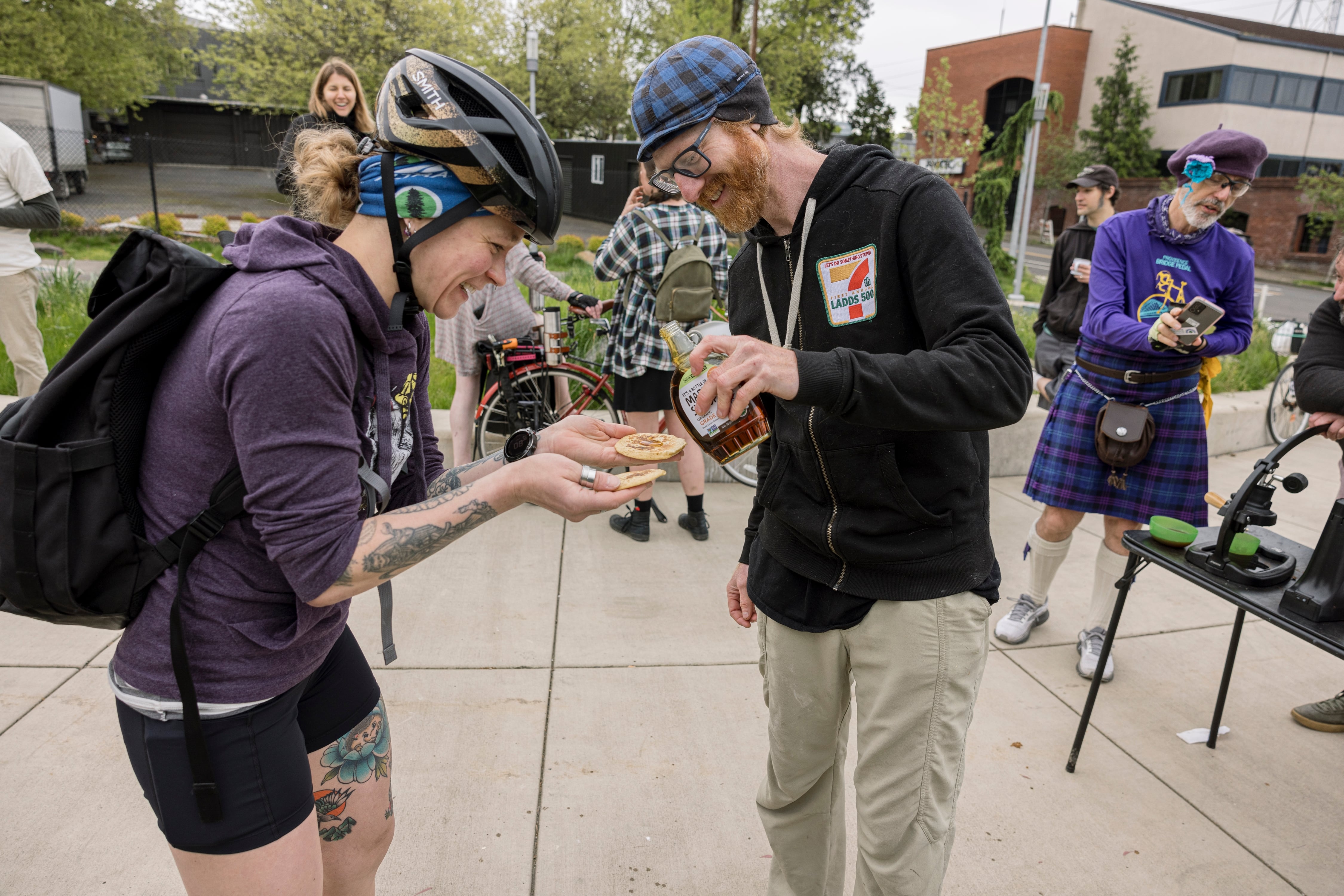 Volunteer Lance Poehler (blue cap) provides plates of fresh-cooked pancakes for people who want to stop and eat, but some, like commuter Leah Brown, take theirs to go.