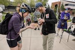 Volunteer Lance Poehler (blue cap) provides plates of fresh-cooked pancakes for people who want to stop and eat, but some, like commuter Leah Brown, take theirs to go.
