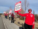 People stand in a line outside a hospital, holding up signs that read "OFHNP Healthcare Workers On Strike Against Unfair Labor Practices."