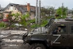 A Russian military vehicle painted with the letter Z drives past destroyed houses in the Ukrainian city of Mariupol on Wednesday.