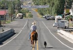 FILE - In this image from 2007, a person rides a horse through Paisley, Ore. while a dog follows. The small town hosts an annual Mosquito Festival.