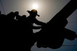 FILE - A linesman works on power lines under the morning sun, July 12, 2024, in Phoenix.