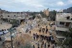 Palestinians look at a residential building destroyed in an Israeli strike in Deir al Balah on Monday, March 25, 2024.