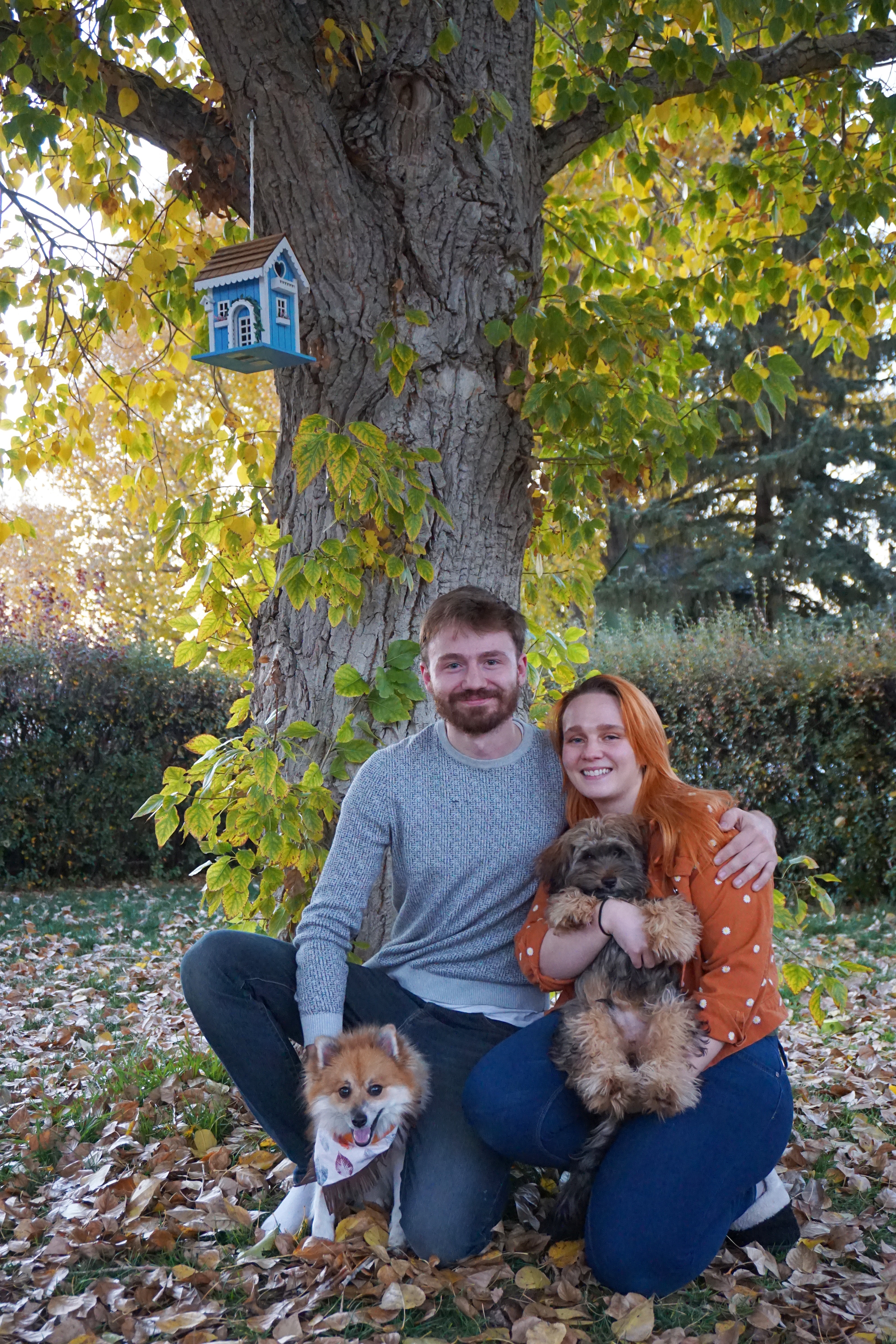 Sean Thornton and Reesie Lane sit under a tree with their dogs.