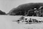 In this image from 1892, people gather on the beach below Heceta Head. Excavation for the lighthouse can be seen on the bluff.