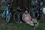 A man sits in the nude and waits for the ride to begin. The World Naked Bike Ride is an all-ages for cyclists of all skill level.