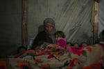 Reda Abu Zarada wraps herself and her grandchildren in blankets as they prepare to sleep in their tent at a camp in Khan Younis, Gaza Strip, Thursday Dec. 19, 2024.