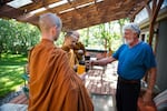 Ray Klebba, right, hands tea to Ajahn Kassapo on alms round. Klebba and his partner, Shelley Baxter, contribute food to the monks throughout the week.