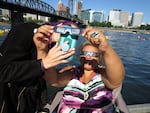 Costume designer Lisa Taylor helps her friend try and get a good picture of the solar eclipse on a dock in downtown Portland.