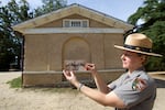 A woman in a National Park Service uniform holds up a Civil War-era photo of Selina Norris Gray, at the site where it was taken at what is now Arlington National Cemetery.